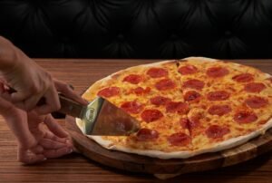 Fresh pepperoni pizza being sliced, highlighting delicious cheese and toppings.