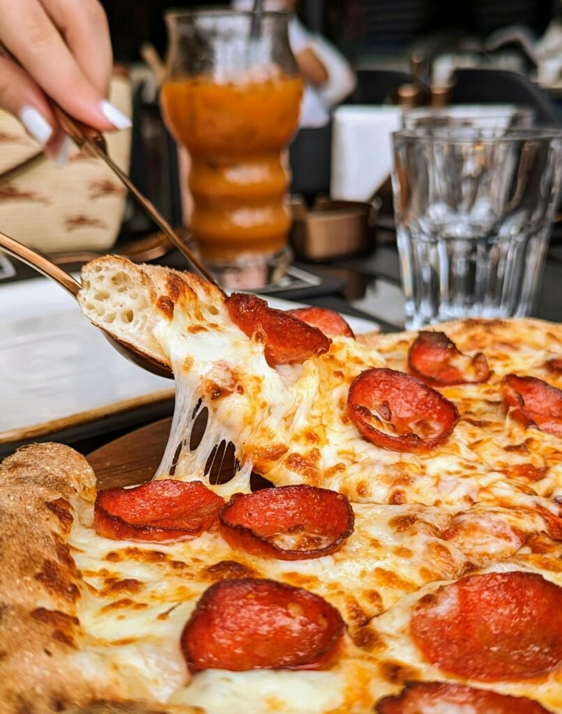 pexels-photo-17708242-17708242 Close-up of a mouthwatering pepperoni pizza slice with melted cheese being served in a restaurant setting.